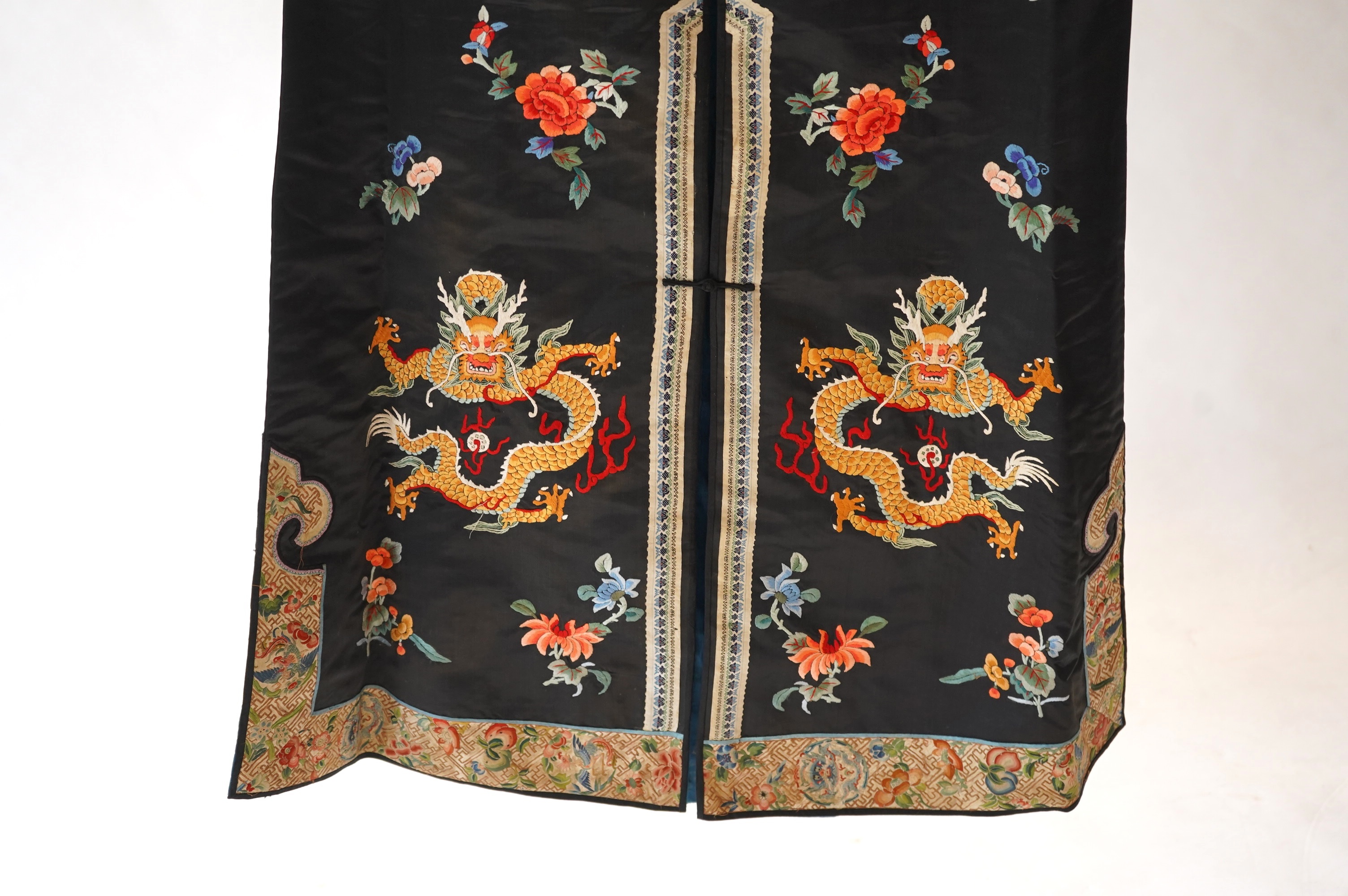 An early 20th century Chinese blue satin silk embroidered dragon robe, embroidered with five claw dragon symbols with flaming pearls, surrounded by bats and flower motifs, with gold thread embroidered dragon sleeve bands